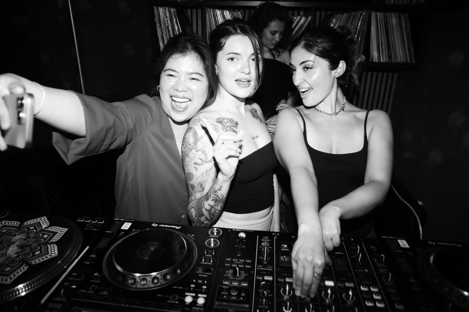 Friends laughing behind the DJ decks in the Stereo 41 lounge