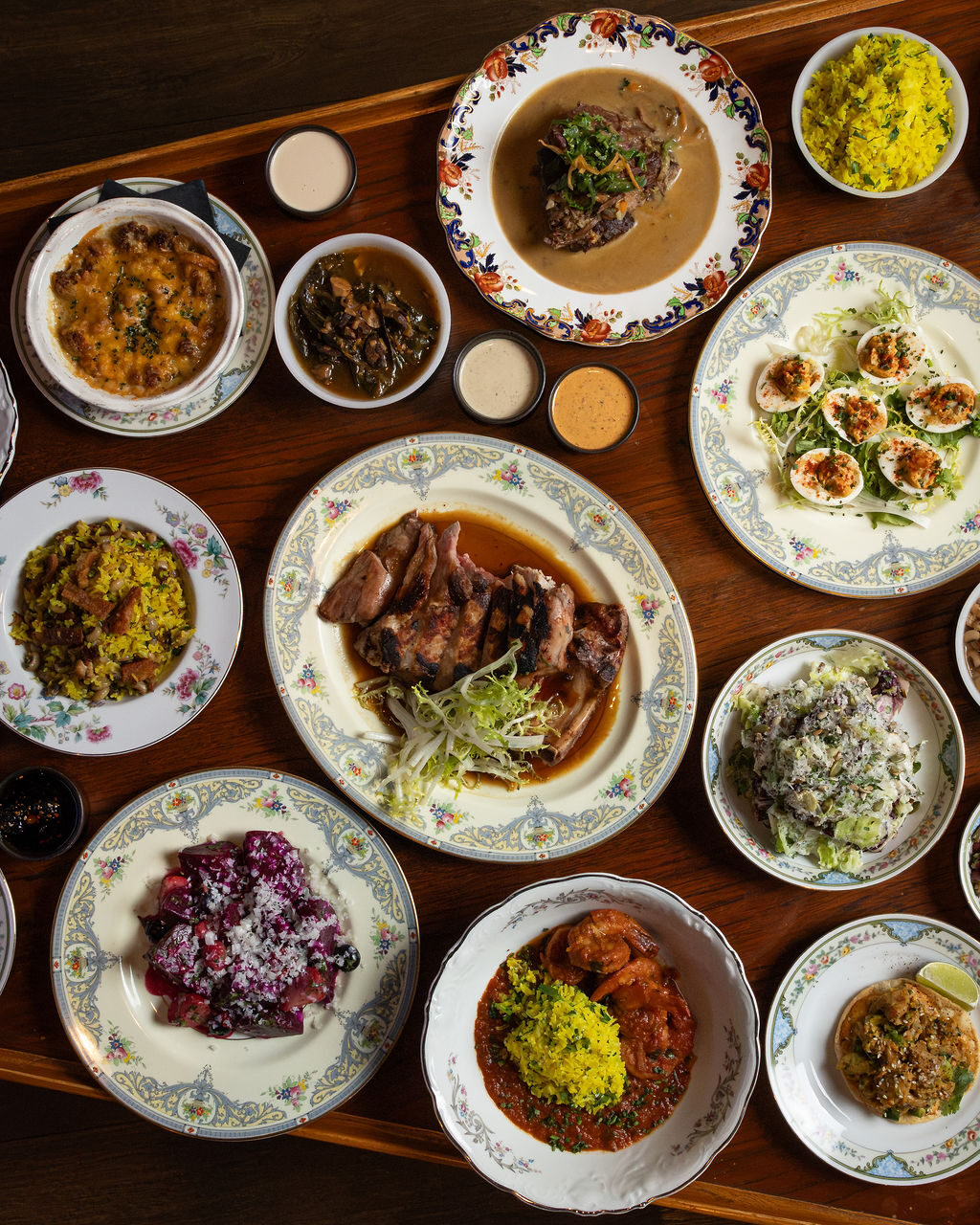 Overhead spread of Southern dishes on vintage china at Stereo 41 - pork chop, deviled eggs, shrimp creole and sides